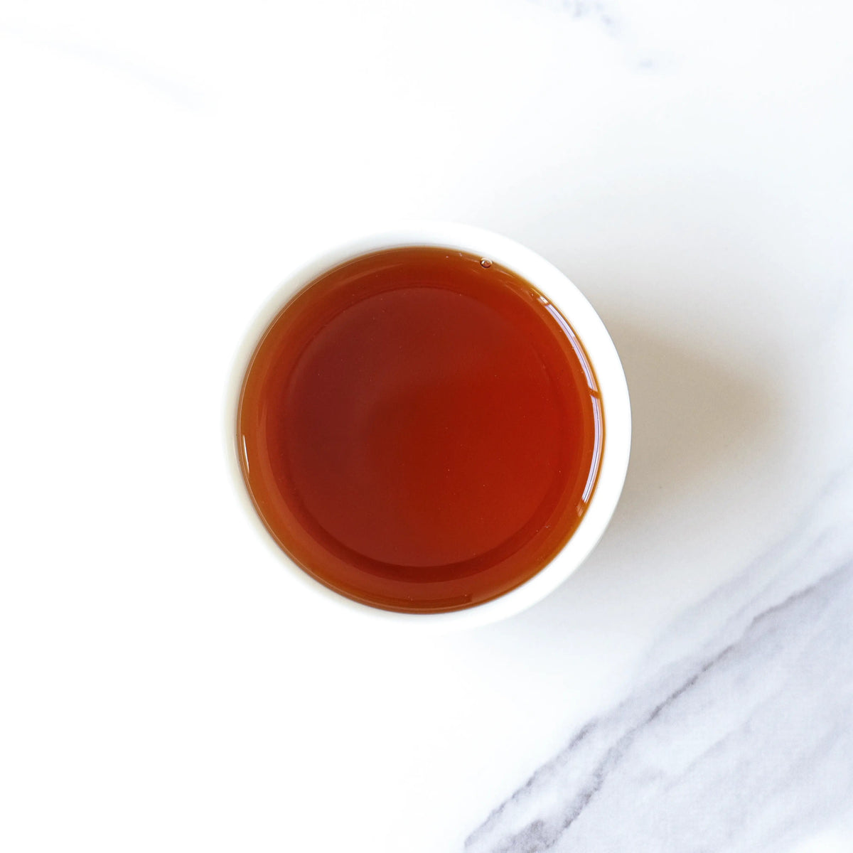Dark amber liquor brewed from CHICHATEA Mini Chrysanthemum Pu-erh Tea Cakes