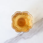 A top view of a honeycomb-patterned amber glass bowl, perfect for enjoying My Store’s Da Hong Pao Oolong Tea, set on a white marble surface with elegant gray veining.