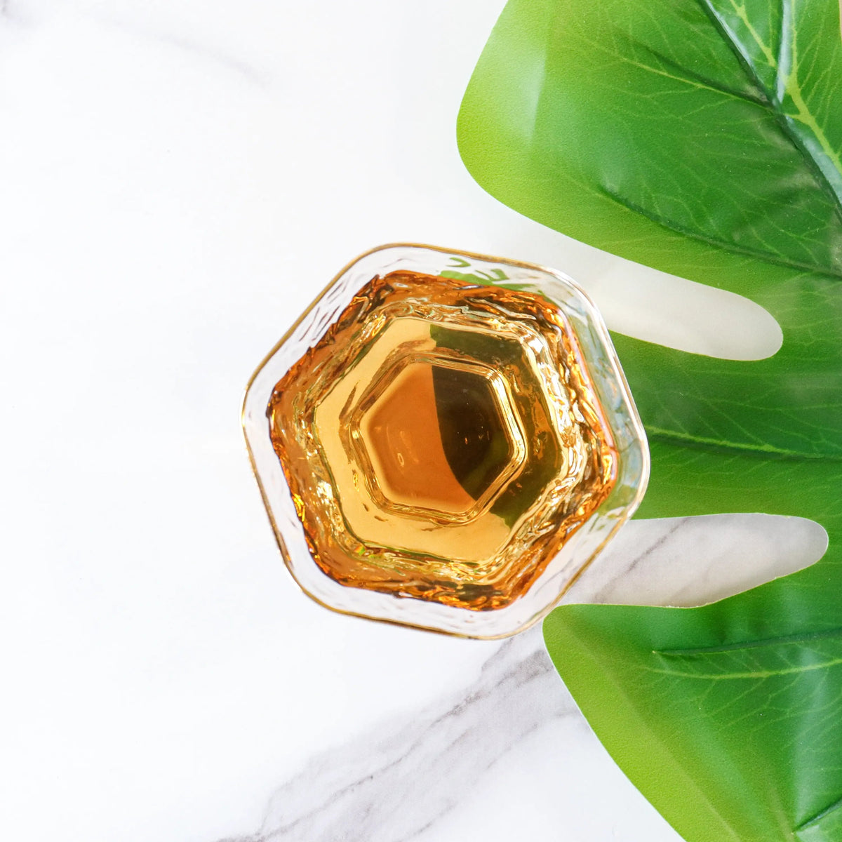 CHICHATEA Dianhong Rose Black Tea brewed amber liquor in a glass cup on a white marble surface