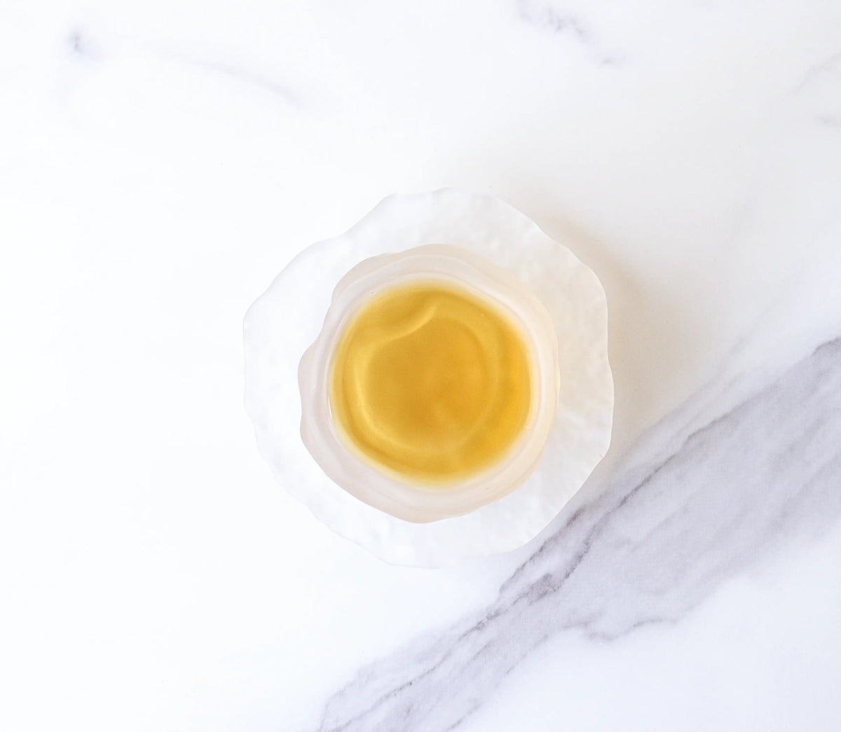 Brewed Dianhong black tea with golden liquor in a clear glass cup on marble.