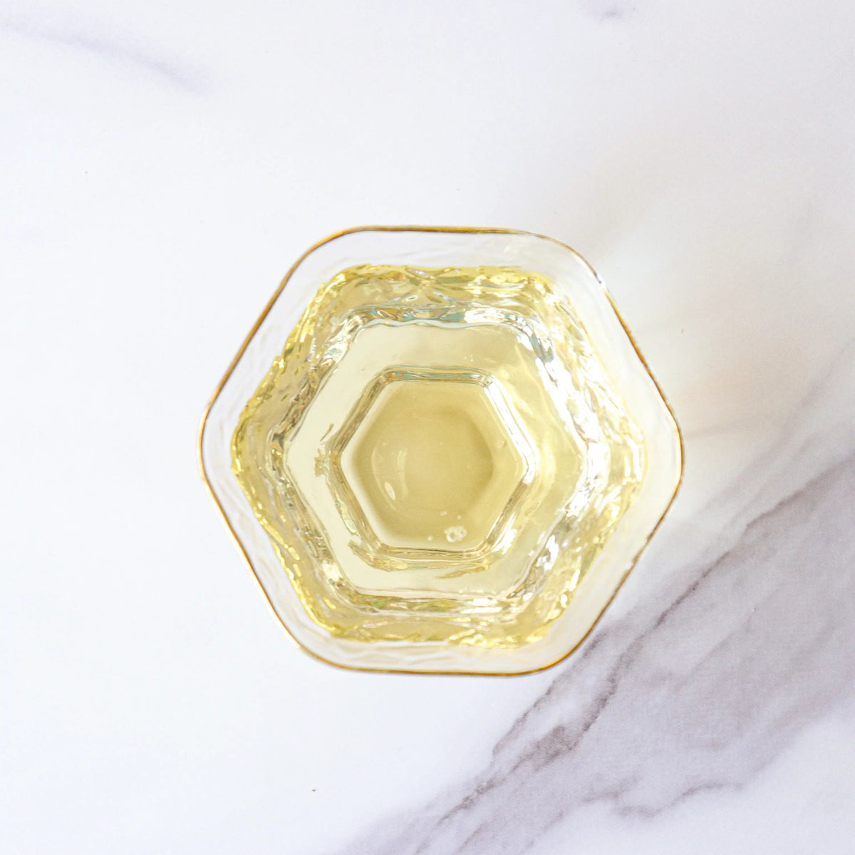 Light yellow Emei Maofeng Green Tea liquor in a hexagonal glass cup