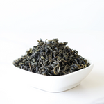 A white square bowl holds loose leaf Gardenia Green Tea by My Store against a plain white background—a simple, inviting display of wellness tea ready to brew.