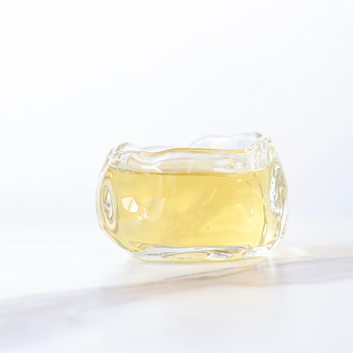 Light yellow Gardenia Green Tea liquor in a clear glass cup