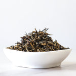 A white bowl of My Store’s Jin Jun Mei Black Tea loose leaves sits on a white surface, highlighting the tea’s Wuyi Mountain heritage against a plain background.