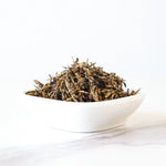 A white bowl filled with loose My Store Keemun Black Tea, the Queen of Black Tea, sits on a white marble surface against a plain white background.
