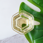 Brewed Longjing Dragon Well Green Tea in a small glass cup on white marble.
