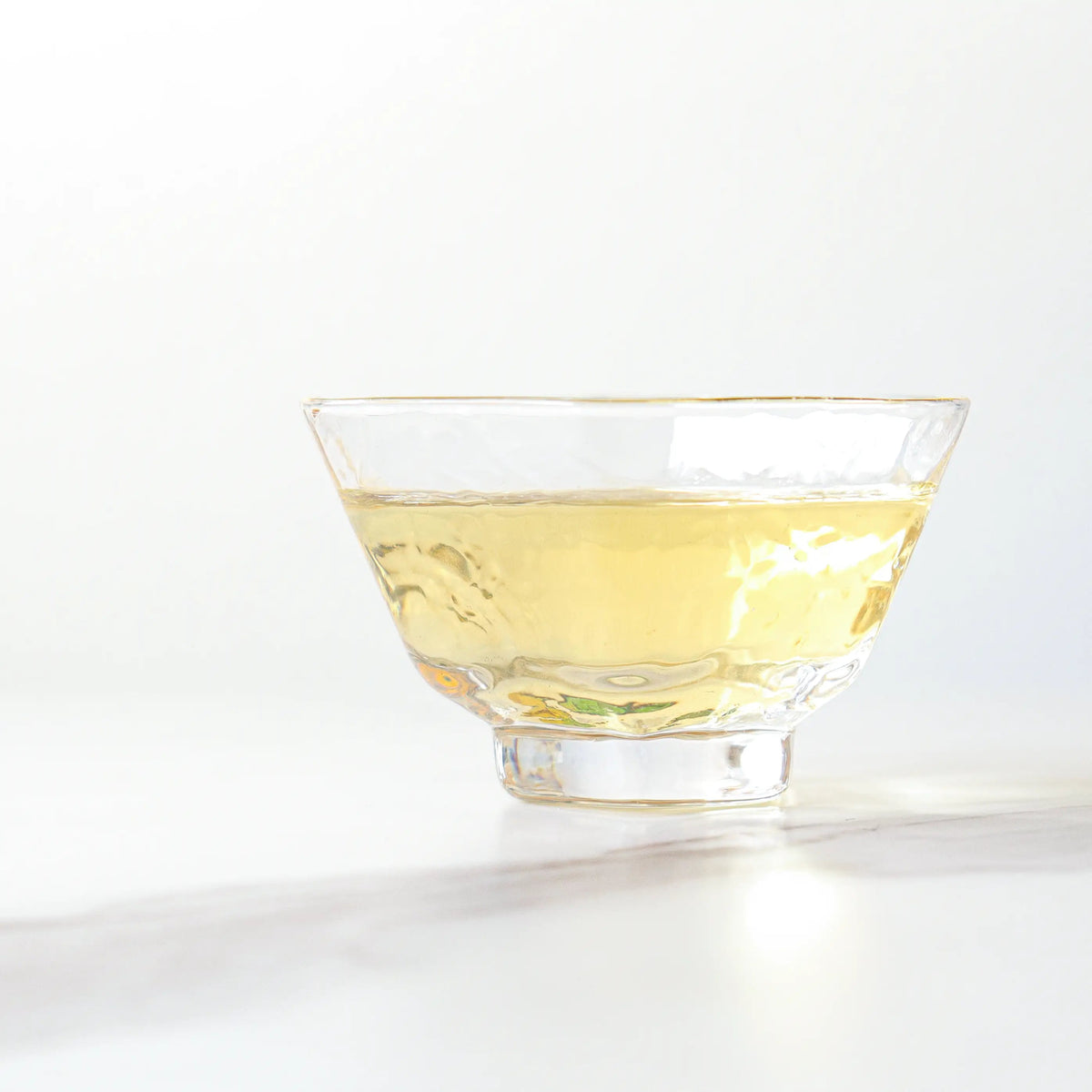 Brewed Longjing Dragon Well Green Tea with pale golden-green liquor in a glass cup.