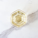 A hexagonal glass filled with My Store's Tie Guan Yin Oolong Tea, famous for its orchid aroma and light color, is placed on a white marble surface.