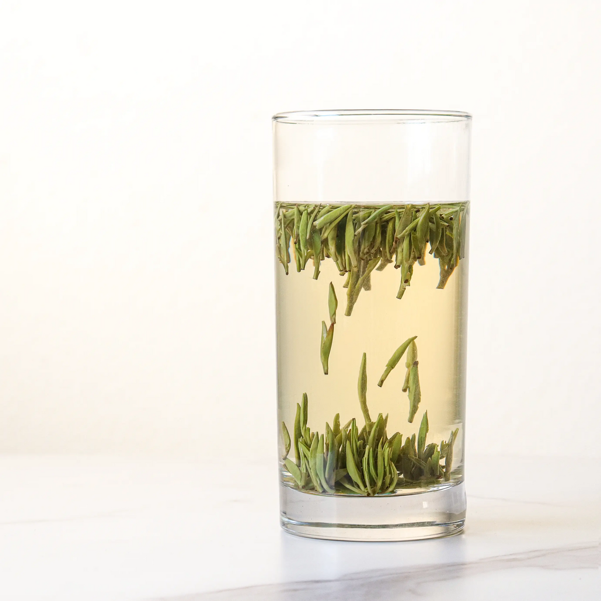 Zhu Ye Qing Green Tea brewed in a glass with leaves settled at the bottom